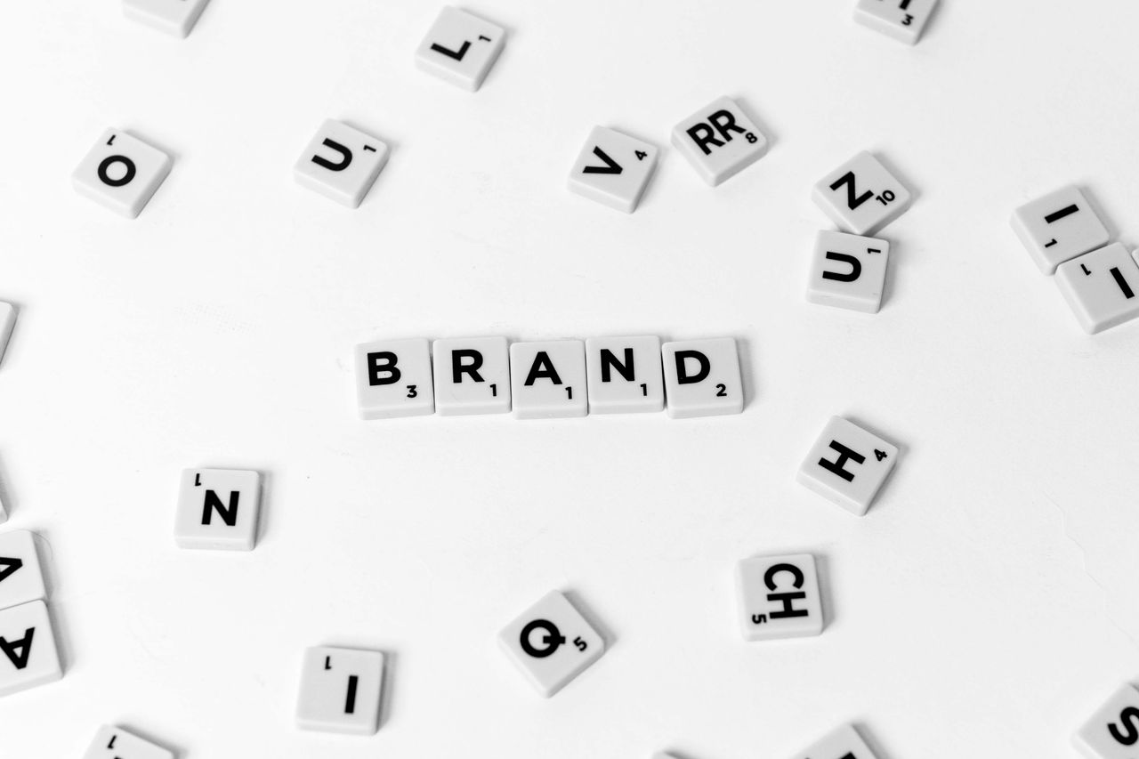 services-01 A flat lay of scattered letter tiles forming the word BRAND on a white background.